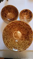View of the three graduated Bennington bowls from above showing their mottled brown glaze pattern and size differences.