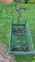 Top-down view of the green metal mesh garden cart showing the interior and the metal handle with black cushioned grip.
