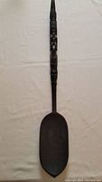 Full length photo of the large wooden ceremonial spoon showing the carved handle and large bowl.