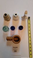 Top view photo showing three vintage pie funnels, one Victorian glass ink well, two small blue bottles, and wooden nut cracker, size comparison with measuring tape.