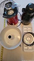 Top view of popcorn maker with clear scoop, coffee flask, bundt cake tin, steel colander, and ice tray laid out on a table.