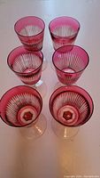 Set of six cranberry overcut wine glasses viewed from above showing the clear-cut vertical stripes and the cranberry dipped color.