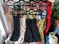 Overview of nine women's dresses hanging on hangers, various colors and styles.