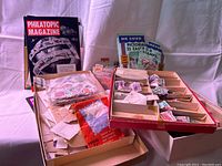 Overall view of two boxes containing loose stamps, envelopes with stamps, and some stamp packets.
