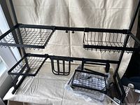 Black adjustable metal over the sink drying rack with wire baskets and utensil holders shown fully assembled and standing upright.