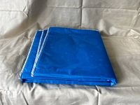 Blue twin size cooling mattress pad folded neatly on a beige background, photo taken to show folded state and condition.