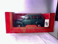 Side view of dark green die cast metal GMC Carryall Suburban model car in original red box.