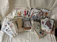 Photo of a bundle of vintage sewing patterns featuring Butterick, Simplicity, Kwik Sew, and a cross-stitch catalog, depicting various women's clothing designs.