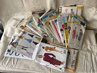 Photo of multiple vintage sewing pattern envelopes spread on a surface showing styles for women's dresses and garments.