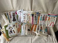 A collection of 23 vintage sewing patterns from brands such as Butterick, Simplicity, and Vogue, depicting various women's and children's clothing designs.