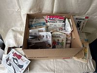 Box of assorted vintage sewing patterns with Butterick, Simplicity and Basic brands visible.