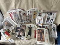 Image of assorted vintage sewing patterns from various designers including Vogue, Burda, Chloe, Pollera. Patterns packaged in clear plastic or paper envelopes with model photos visible