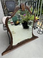 Full view of the antique walnut wood dresser mirror showing curved top and base with carved detail.