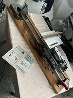 Full top-side view of the vintage Cummins Do-It Shop Model 440 power tool on a wooden base with manual beside it.