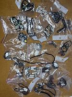 Overview of multiple necklace pieces in individual plastic bags showing diverse styles and pendants
