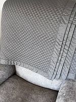 Close view of the dark khaki green/grey diamond quilted cotton bedspread draped over a chair, showing the texture and solid border.