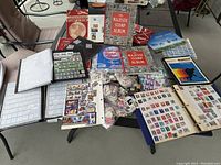 Overview of multiple Majestic stamp albums, loose stamps in bags, and various thematic sheets spread on a table.