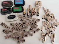 Overall lot showing multiple wooden stamps with rubber faces and four ink pads. Stamps have small realistic figures, words, symbols including smiley faces, flowers, and animals. Ink pads are Craft Smart and Brilliance brands in multiple colors.