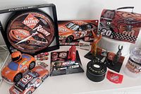 Wide view of the NASCAR Tony Stewart collectible lot showing a wall clock, diecast cars, lunchbox, figurines, and other memorabilia all themed with The Home Depot branding and number 20.