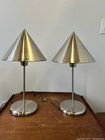 Front view of both lamps on wooden surface against white wall.