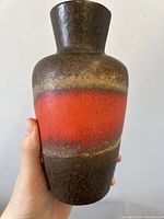 Close-up of ceramic vase showing detailed textured glaze with red and brown color bands.