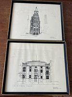 Two framed pen and ink prints displayed flat on wooden surface: Upper is Old Courthouse, lower is Flatiron Hotel.