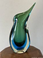 Front view of the vase showing the green interior layer, blue middle layer and clear outer glass with an elegant curved shape.