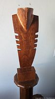 Front view of the tall carved wooden jewelry display stand shaped as an abstract torso.