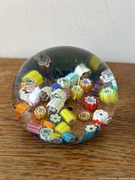 Side view showing colorful millefiori canes embedded in clear glass with bubbles and textured base.