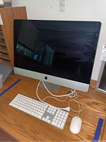 Front view of iMac showing display, stand, keyboard and mouse on table