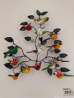 Full view of the bird wall art showing multiple colorful wooden birds on metal branches with metal leaves.