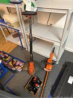 Photo of Black and Decker Grass Hog string trimmer, electric hedge trimmer, and battery packs on the floor