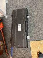 Closed black plastic carrying case for DeWalt saw, on carpeted floor