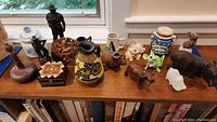 Top view of all items on shelf showing diverse collection of jars, vases, animal figurines, trinket box, and miniature mugs