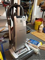 Full front view of Kenmore Intuition upright vacuum with hose and wand attached in a household setting.