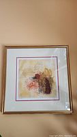 Framed abstract art piece with gold colored frame on wall