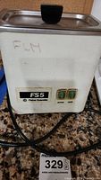 Front view of white rectangular Fisher Scientific Sonicator Jewelry Cleaner model FS 5 with control buttons and power cord.