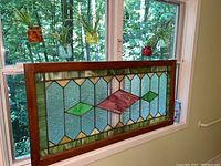 Stained glass panel on windowsill with hanging jars visible above