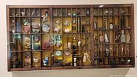 Front view of wooden wall mount cubby filled with assorted collectibles including shells, figurines, keys, and small jars.
