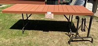 Full top view of the folding table on a grass lawn with extra metal folding legs placed to the side