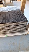 Stack of gray carpet tiles showing thickness and edges.