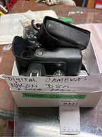 Box with Nikon D80 camera in black leather case and handwritten label showing Nikon D80 with 200mm lens