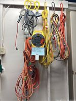 Photo showing various extension cords, the yellow cord reel, and two work lights hanging on a wall.