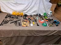 Overall view of garden tools, irrigation parts, hand tools, and decorative items on a cloth-covered table.