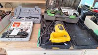 Photo showing Superior biscuit joiner, DeWalt reciprocal saw, and Dremel Moto tool kit laid out on a wooden surface with cases.