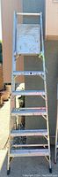 Full front view of the 8ft aluminum platform ladder showing the platform and steps with paint marks and weathering.