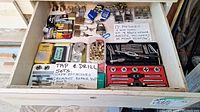 Drawer with labeled sections containing 17 padlocks, tap and drill sets, screw extractors, grommet repair tools, and brass grommets.