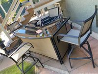 Overall photo of the patio bar set showing the rectangular bar with glass top and four swivel chairs with fabric seats and backs.