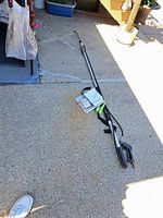 Full length shot of the aluminum pressure washer extension wand lying on a concrete surface showing its length and structure.