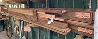 Overall view of three bundles of red cedar boards on outdoor shelving with handwritten tags